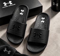 Pair of black Under Armour men's slides on grey stone