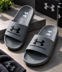 Pair of grey Under Armour men's slides on stone steps